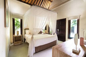 A bedroom with a canopy bed, a bedside table, a dresser, and a mirror. - Kebun Villa Canggu (Canggu)