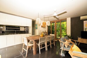 Eine moderne Küche mit weißen Schränken, ein Essbereich mit Holztisch und Stühlen sowie ein Deckenventilator.