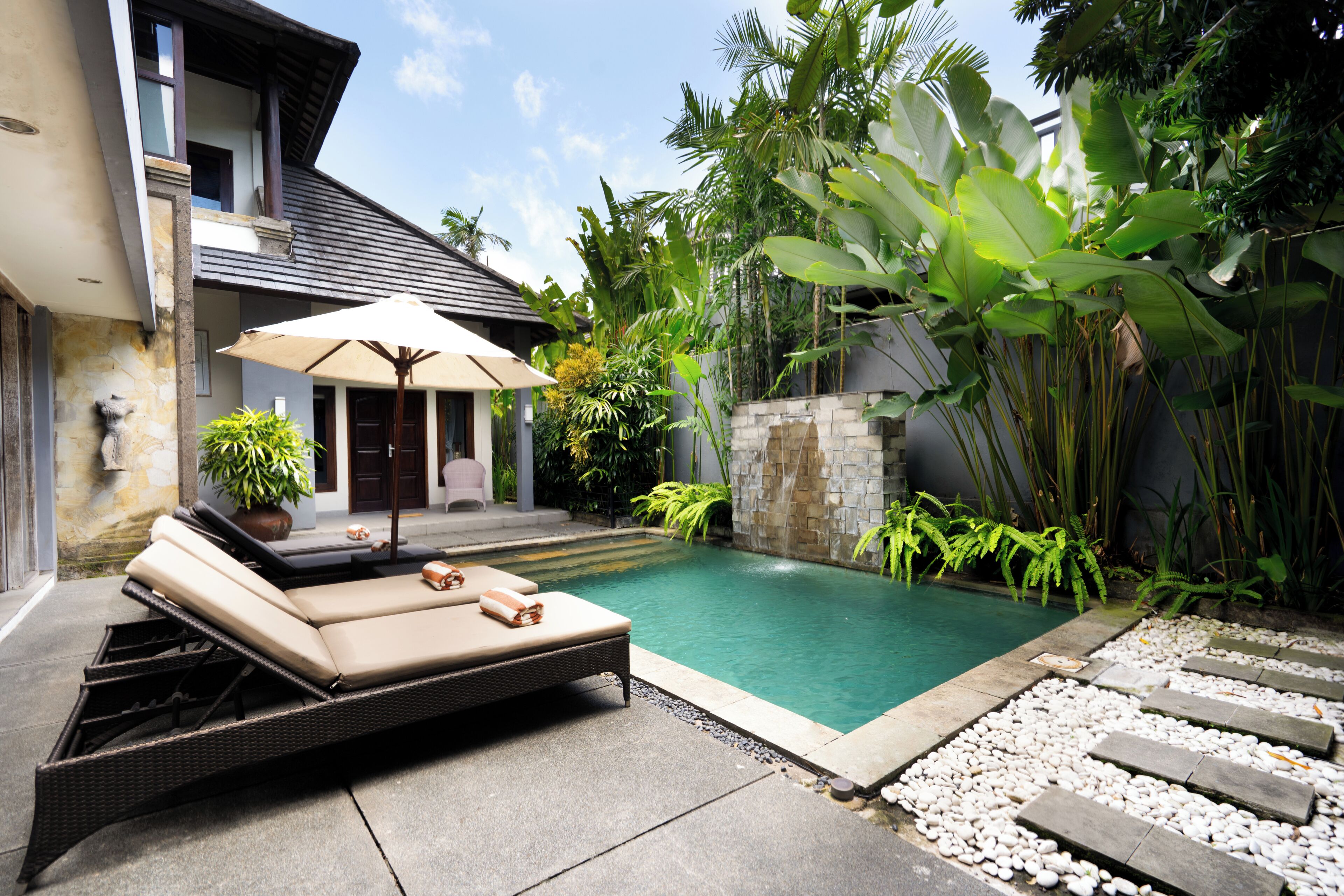 A pool area with lounge chairs and a stone wall.