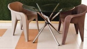 Een eethoek met een groene wand, een glazen tafel en twee stoelen.