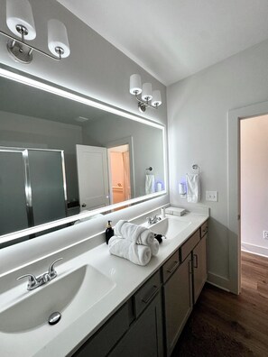 A modern bathroom with a large mirror, two sinks, and a walk-in shower. - Modern Townhome - 2 Bedroom / 2 Bathroom - Beltline, Grant Park, Downtown, Zoo (Atlanta)