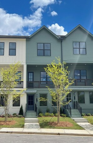 A two-story residential building with a front porch, a small tree, and a clear blue sky. - Modern Townhome - 2 Bedroom / 2 Bathroom - Beltline, Grant Park, Downtown, Zoo (Atlanta)