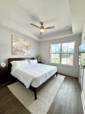 A bedroom with a bed, a ceiling fan, a window with a view, and a painting on the wall. - Modern Townhome - 2 Bedroom / 2 Bathroom - Beltline, Grant Park, Downtown, Zoo (Atlanta)