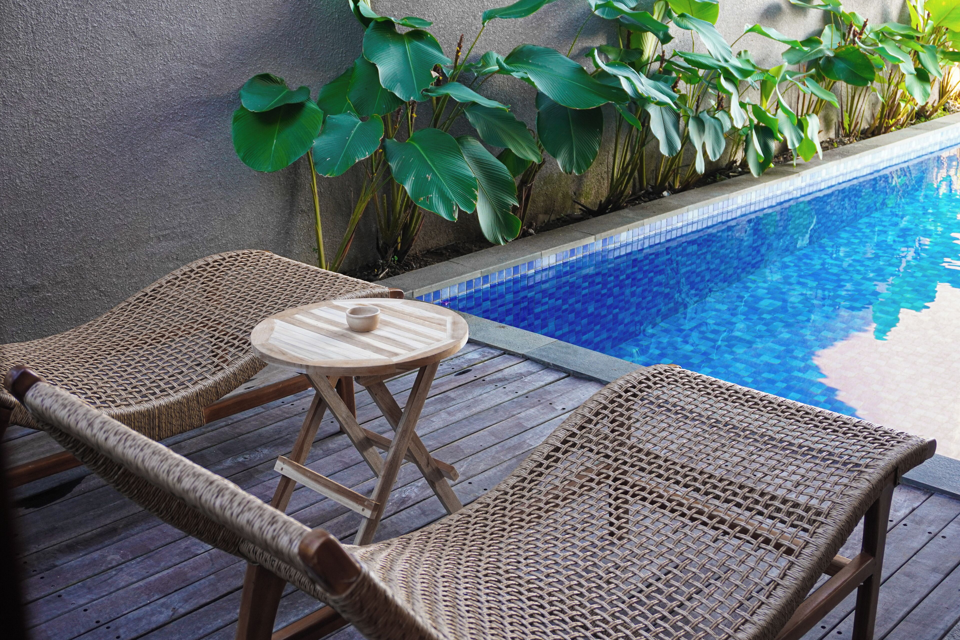 A poolside area with wicker lounge chairs and a small table.