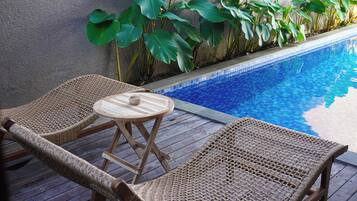 A poolside area with wicker lounge chairs and a small table.
