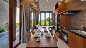 Une cuisine moderne avec un coin repas, de grandes fenêtres et une vue sur l’extérieur.