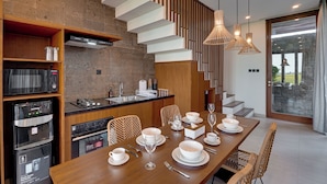 Una cocina moderna con comedor, que presenta una mesa de madera preparada para una comida, horno empotrado y un amplio ventanal con vistas.