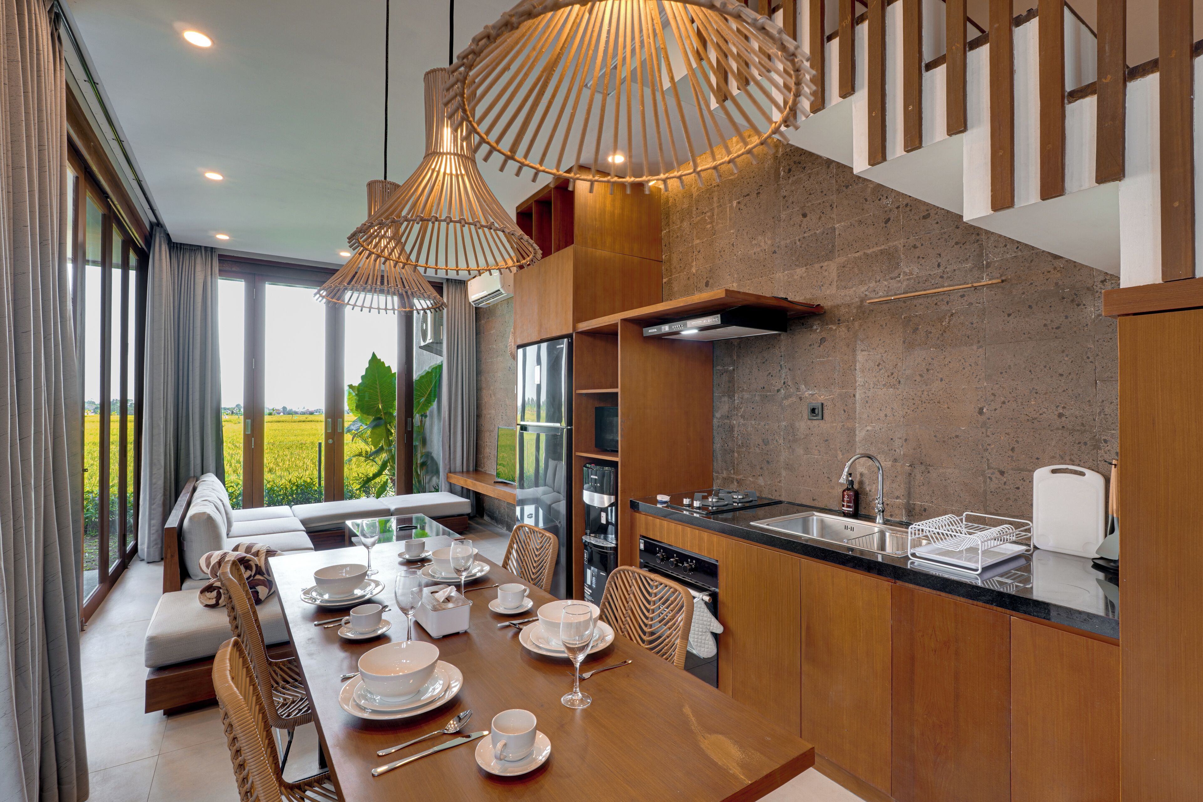 Una cocina moderna con comedor, ventanas amplias y vistas a un paisaje verde.