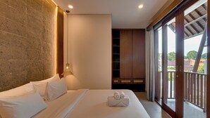 Une chambre d’hôtel avec un grand lit, une armoire, une fenêtre donnant sur un beau paysage et une lampe suspendue.