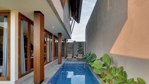 Un espace piscine extérieur moderne, doté d’une piscine à l’eau d’un bleu limpide, d’une terrasse en bois et d’un mur en pierre.