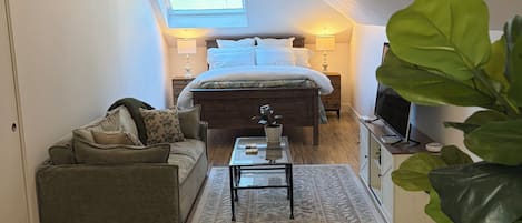 Une chambre à coucher avec un lit, une table de chevet, un téléviseur et une grande fenêtre.