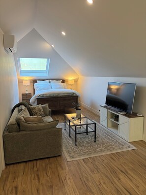 A modern loft bedroom with a large bed, a TV, and a cozy seating area. - Sonoma Sky Suite: Private Hot Tub & Entrance, Couples Retreat (Sonoma)