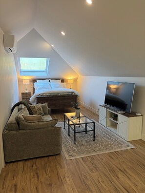 A cozy bedroom with a bed, a TV, a sofa, and a small table. - Sonoma Sky Suite:  Private Hot Tub, Outdoor Space, Entrance….couples getaway. (Sonoma)