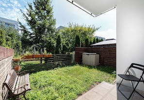 A patio area with a wooden bench, a metal fence, and a shed. - Royal Wilanów Charming Apartment (Warszawa)