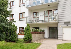 A multi-story residential building with a balcony, a brick wall, and a small garden area. - Royal Wilanów Charming Apartment (Warszawa)