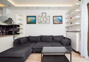 A modern living room with a sectional sofa, a glass coffee table, and white shelving units. - Royal Wilanów Charming Apartment (Warszawa)