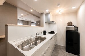 A compact kitchen with a stainless steel sink, a stove, and a black refrigerator.