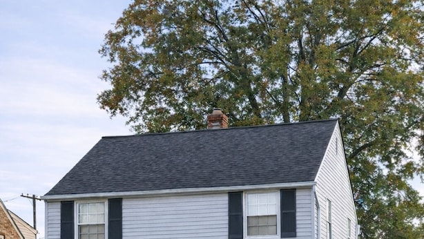 A two-story house with a front porch, a mailbox, and a welcome sign.