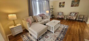 Un salon comprenant un canapé, deux fauteuils, une table basse, une lampe et un tapis.
