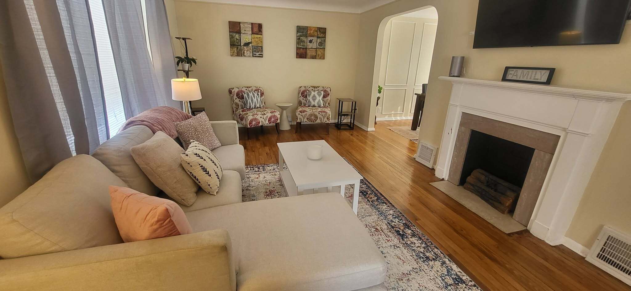 Een woonkamer met een bank, fauteuil en een open haard.