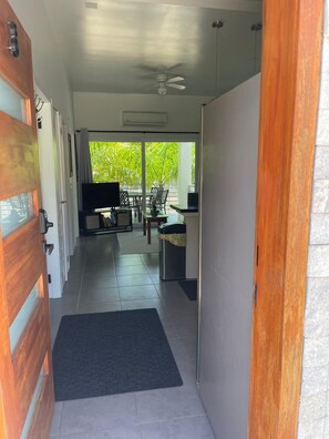 A hallway leading to a balcony with a TV, seating area, and a ceiling fan. - Beautiful condo, located on Roatán's best beach, just 3 minutes from everything!!🏖 (Roatan)