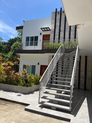 A modern two-story building with a staircase leading to the upper floor. - Beautiful condo, located on Roatán's best beach, just 3 minutes from everything!!🏖 (Roatan)