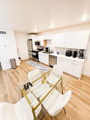 A compact kitchen with white cabinets, a microwave, a stove, and a coffee maker. - The Ascended Retreat (Dallas)