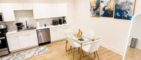 A modern kitchen with white cabinets, a stainless steel dishwasher, and a coffee machine.