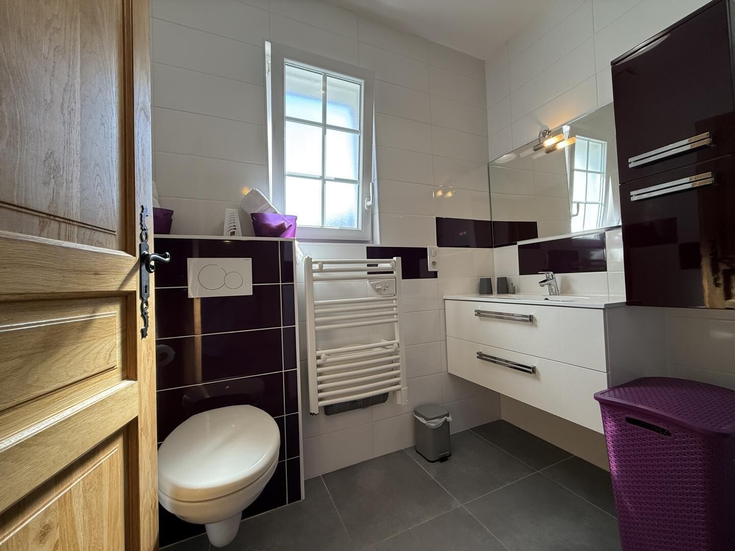 Ein modernes Badezimmer mit Toilette, Handtuchhalter, Spiegel und Mülleimer.