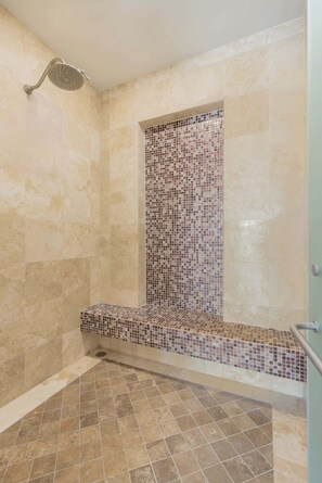 Eine Dusche mit gefliester Wand und einer Sitzbank.