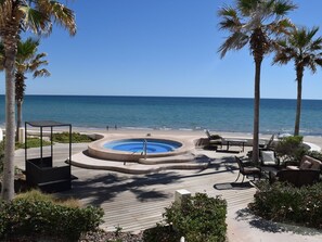 Un espace piscine doté d’un jacuzzi, de chaises longues et offrant une vue sur l’océan.
