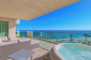 A balcony with a view of the ocean, a hot tub, and outdoor furniture. - Tessoro 204 Beachfront 3BR Luxury Escape (Las Conchas)