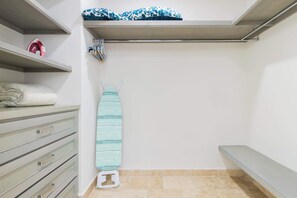 Un dressing avec des étagères, un banc et un appareil à vapeur pour défroisser les vêtements.