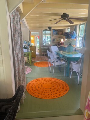 Un coin repas avec une table et des chaises, un ventilateur de plafond et une fenêtre donnant sur un paysage agréable.