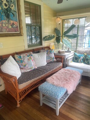 A cozy room with a wicker sofa, a patterned bench, and a window with decorative paper lanterns. - Princess of The Lake (Caroga Lake)