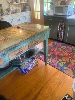 A kitchen with a wooden table, cabinets, and a microwave. - Princess of The Lake (Caroga Lake)