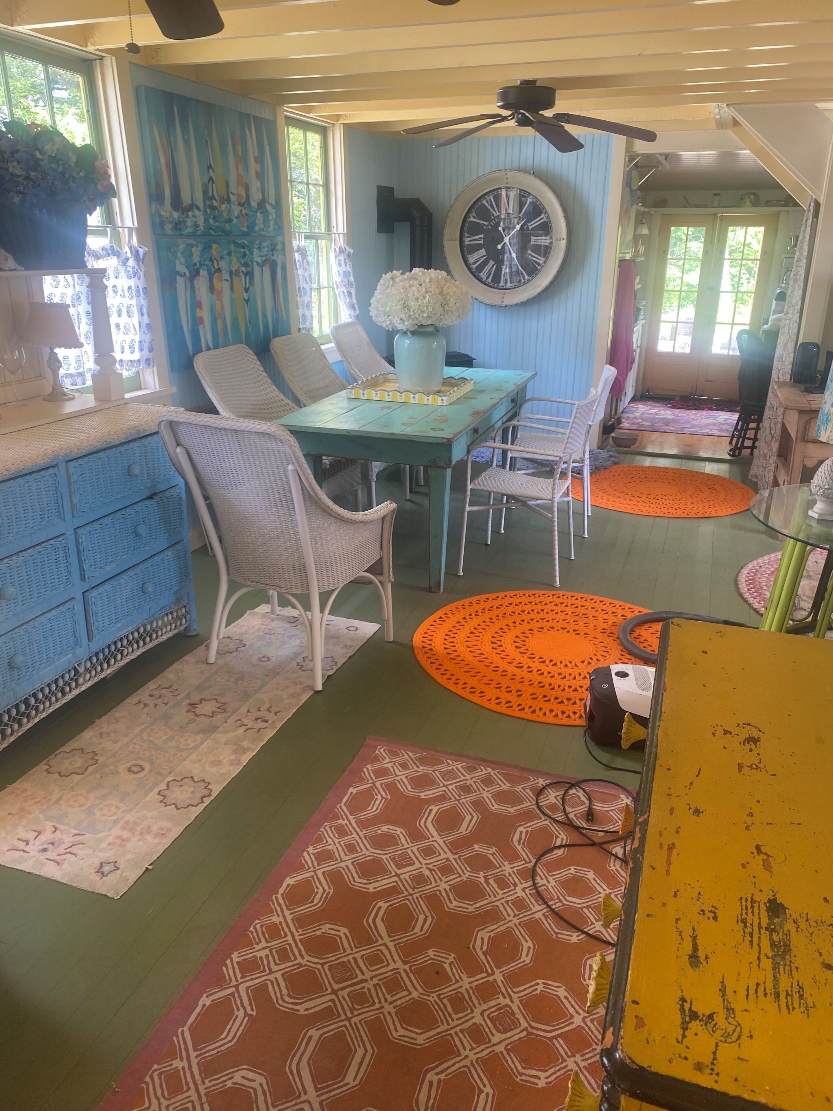 Een eetruimte met een tafel, stoelen en een klok aan de muur.