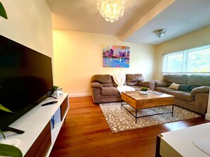 Ein Wohnzimmer mit Flachbildfernseher, zwei Sofas, einem Couchtisch und einem Gemälde an der Wand.