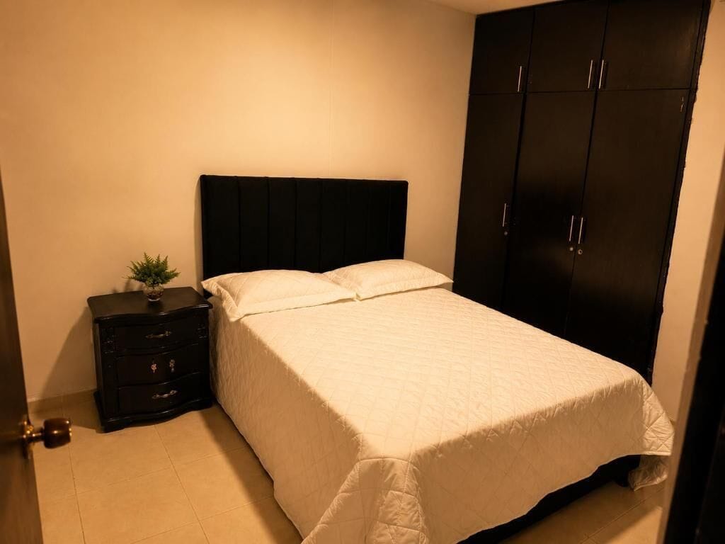 Ein Schlafzimmer mit Bett, Nachttisch, Kommode und Kleiderschrank.