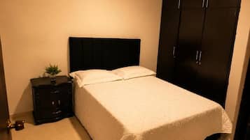 Ein Schlafzimmer mit Bett, Nachttisch, Kommode und Kleiderschrank.