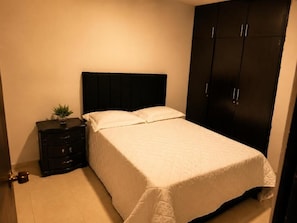 Una camera da letto con un letto, un comodino, una cassettiera e un armadio.