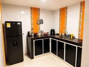 A compact kitchen with a black refrigerator, a coffee maker, and a microwave. - Vrbo Property (Valledupar)