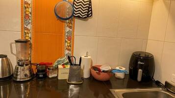 Een keuken met een koffiezetapparaat, een blender, een waterkoker en diverse keukengerei.
