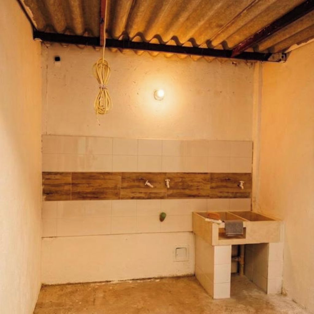 A bathroom with a tiled wall, wooden panel, a sink, and a hanging light fixture.