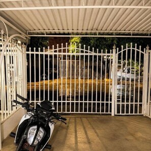 A motorcycle parked under a covered area with a gated entrance.