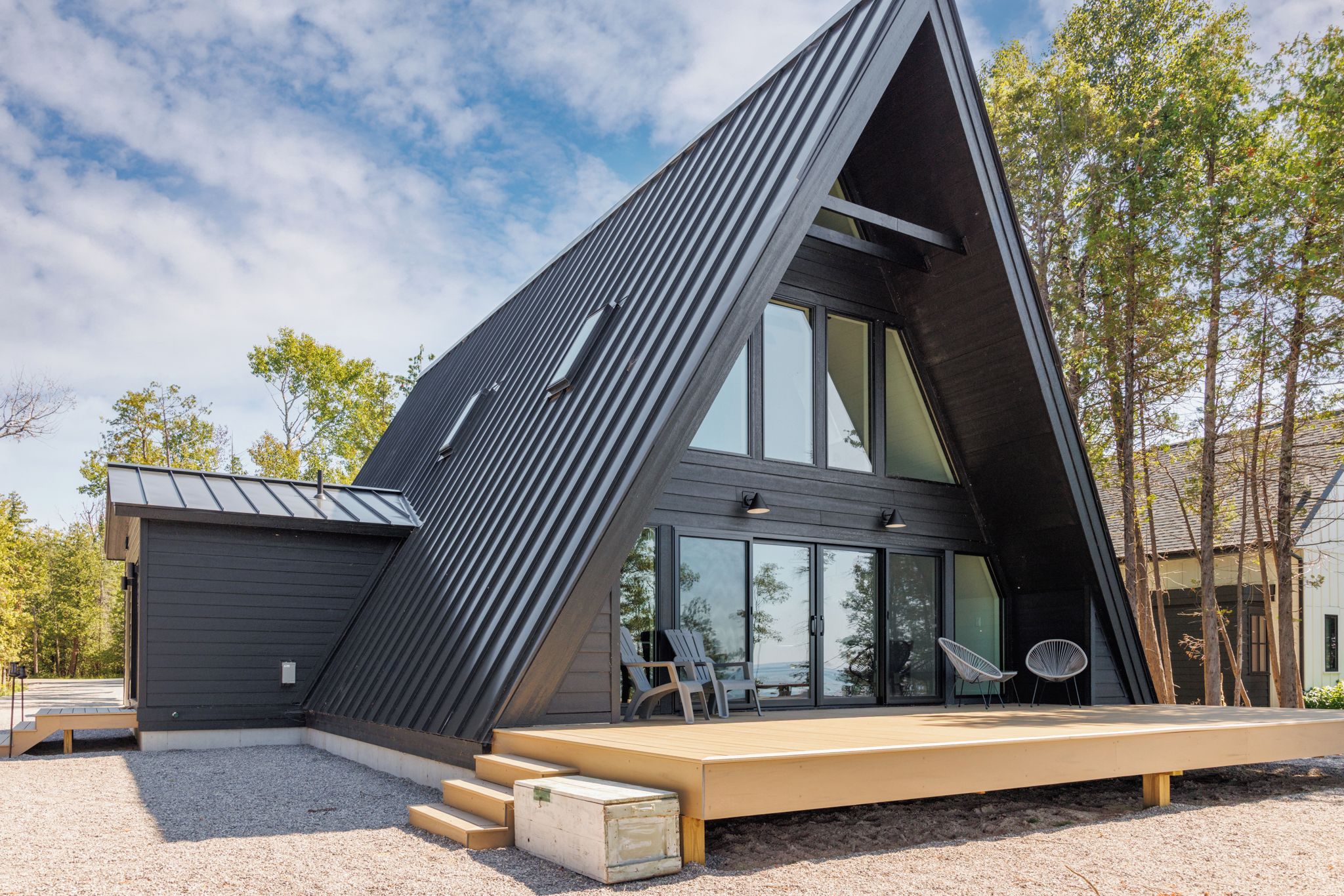 Une maison moderne avec un toit en pente, de grandes fenêtres et une terrasse dotée d’un espace salon extérieur.