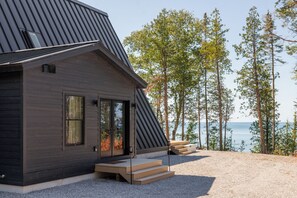 Ein modernes Haus mit geneigtem Dach, großen Fenstern und Blick auf das Meer.