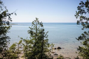 Ein klarer Blick auf ruhiges Wasser, vermutlich ein See oder das Meer, mit einer in der Ferne sichtbaren Küste.
