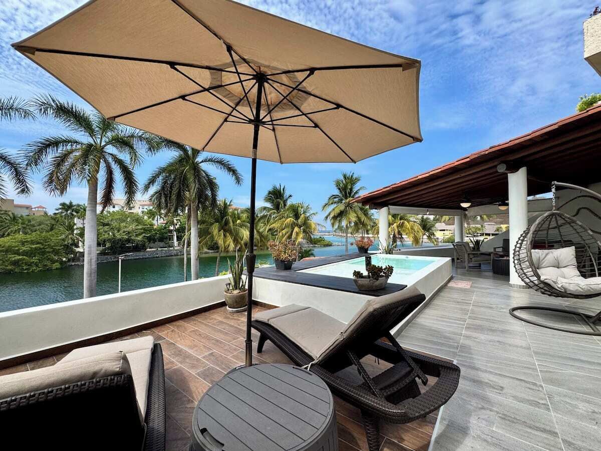 Eine Dachterrasse mit Pool, Liegestühlen und einer Hängematte mit Blick auf ein Gewässer.
