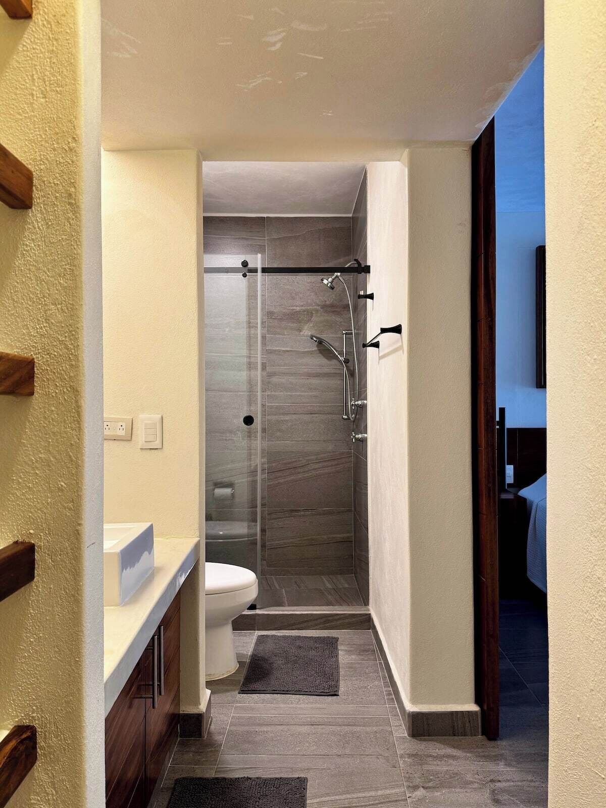 A modern bathroom with a shower, toilet, and sink.